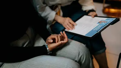 Two people sitting next to each other looking at papers