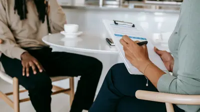 Two people sitting facing each other, one with a clipboard