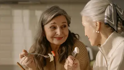 Two people eating a salad in a kitchen